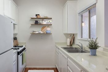 a kitchen with white cabinets and a sink and a window